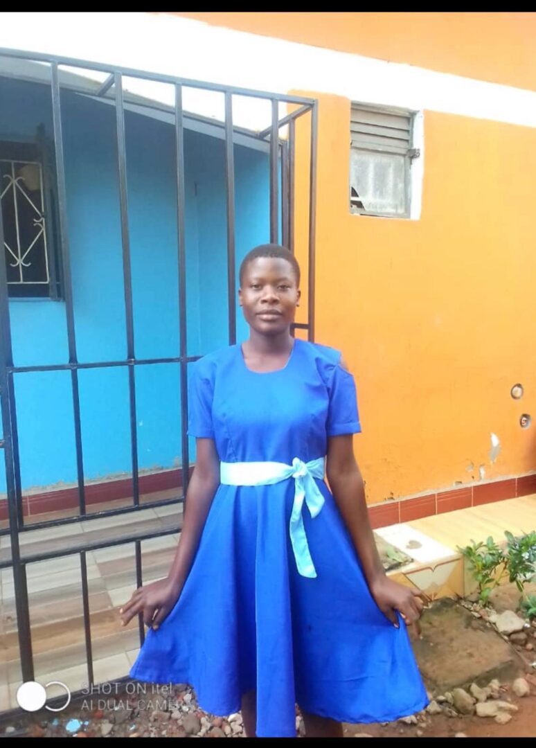 A woman in blue dress standing outside of a building.