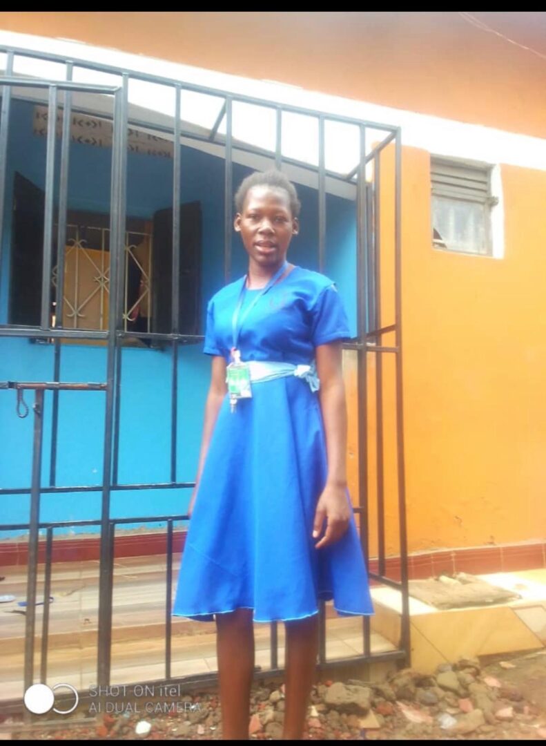 A woman in blue dress standing next to a metal fence.