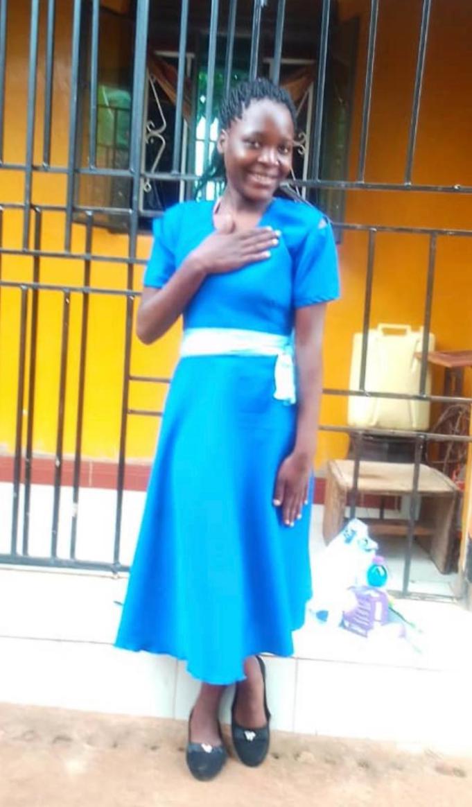 A woman in blue dress standing next to a fence.