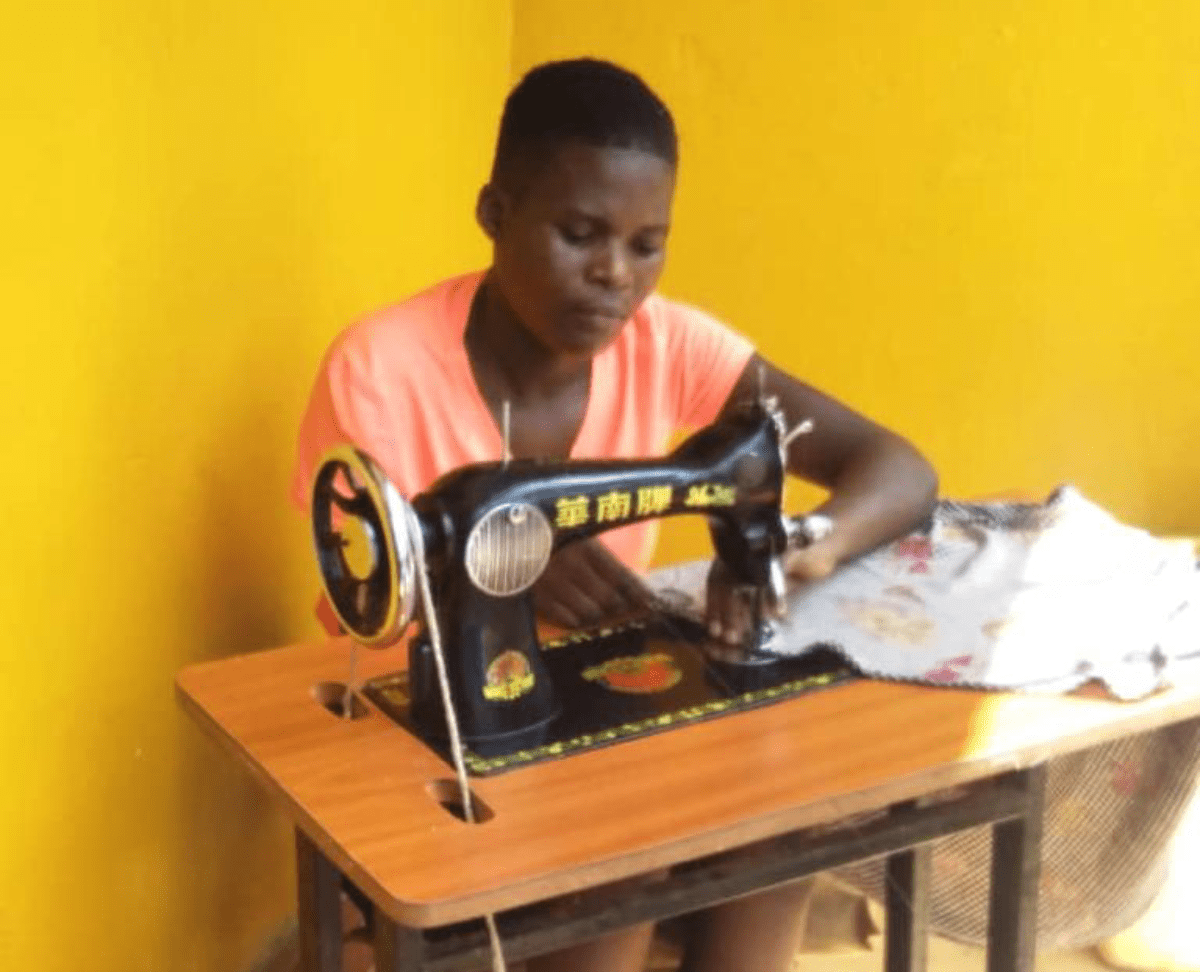 A woman sitting at a table sewing something.